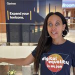 I'm smiling and wearing a shirt with text that says, &ldquo;Digital equality is my jam.&rdquo; Behind me, across the hotel lobby, a large Gartner sign with a stylized coastline reads, &ldquo;Expand your horizons.&rdquo;