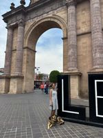 I'm leaning against a large, 3D letter L. An E is next to it, forming the first two letters of the city, Leon. Mylo is lying down on the floor in front of the L, and behind us is a grand stone arch, Arco Triunfal de la Calzada de los H&eacute;roes.