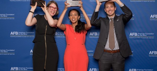 Jenny Lay-Flurrie, Haben Girma, and Jeff Wieland are each holding up a Helen Keller Achievement Award in front of a blue backdrop that says AFB American Foundation for the Blind. Photo by AFB.
