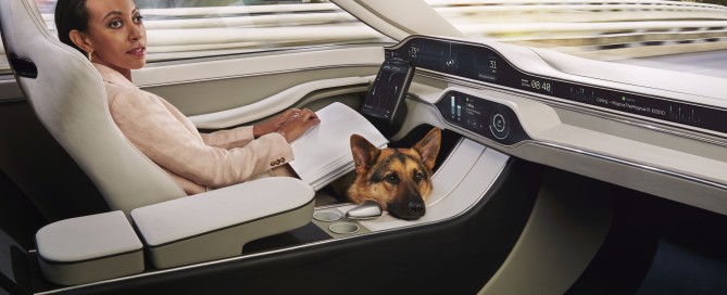 Haben is casually reading a page of braille in the driver’s seat of a car. The driver’s seat doesn’t have a steering wheel, just a touchscreen tablet. In the film Haben controls the tablet with her braille computer. An adorable German Shepherd dog is on the floor, his head peaking up over the central panel.
