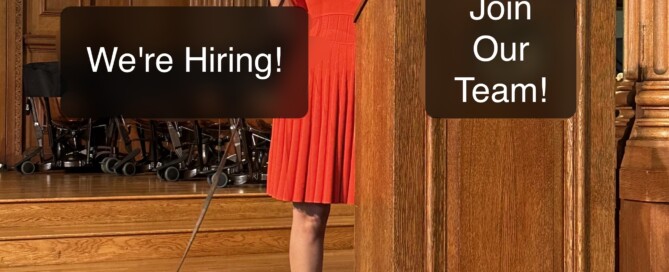 Haben is standing by a podium holding up her braille computer. Her Seeing Eye dog rests, stretched out on the floor by her feet. Text on the image reads: “We’re hiring! Join our team.”