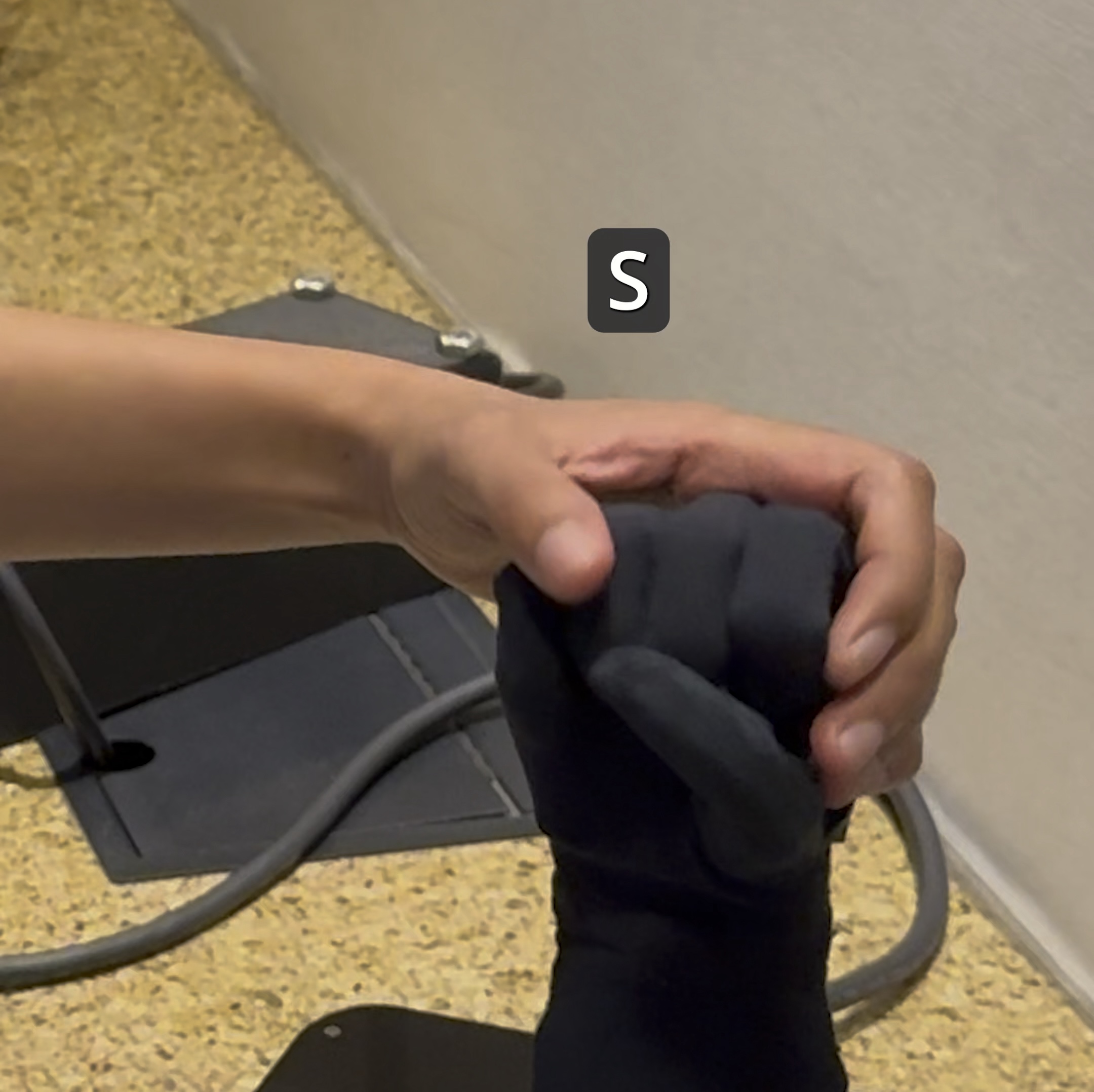 Haben feeling a black robotic hand that is signing the letter "S"