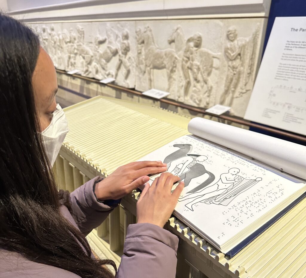 Haben reads the museum's braille brochure.